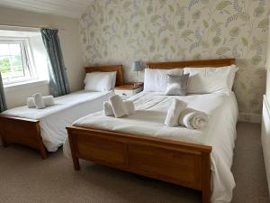a bedroom with two beds with white sheets at The Strontian Hotel in Strontian