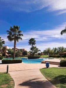 - une piscine avec des palmiers dans un complexe dans l'établissement Prestigia golf pour les familles, à Marrakech