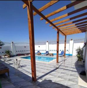 une terrasse avec une piscine et une pergola en bois dans l'établissement Villa Colossi Memnon, à Louxor