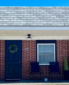 a brick house with a blue door and two chairs at Lincoln House Motel in Lincoln