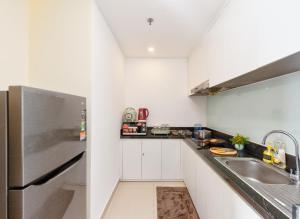 een witte keuken met een wastafel en een koelkast bij S Lux Apartment Virgo in Nha Trang