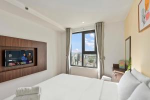 1 dormitorio con 1 cama blanca y TV en S Lux Apartment Virgo en Nha Trang