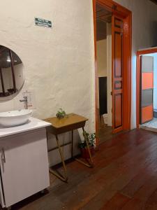 a bathroom with a sink and a table with a mirror at Hotel Colonial Abejorral in Abejorral