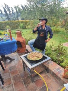 Un uomo in grembiule con una pizza sul tavolo di La Estancia de la Pradera Cabana Fiba a Nobsa