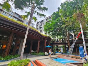 a woman standing next to a building with a swimming pool at La Habana HuaHin by ABCD in Hua Hin