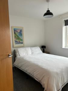 une chambre avec un grand lit avec des draps blancs dans l'établissement Stafford 2 Bedroom Apartment in Prime Location with Secure Parking, à Stafford