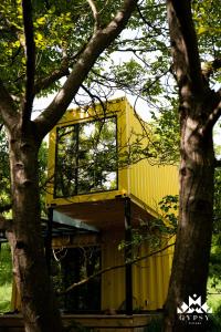 un bâtiment jaune avec une fenêtre dans un arbre dans l'établissement Gipsy Village Park Hotel, à Asuretʼi