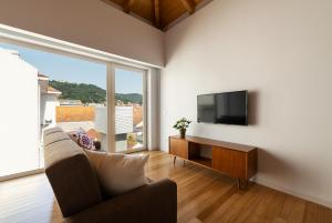 a living room with a television and a couch at Pensao O Laranjeira in Viana do Castelo