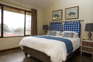 Schlafzimmer mit einem großen Bett mit blauer und weißer Bettwäsche in der Unterkunft Featherbrook Cottage in Tzaneen