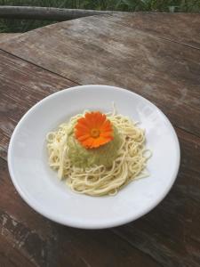 un piatto bianco di pasta con un fiore sopra di Agririfugio Molini a Camogli