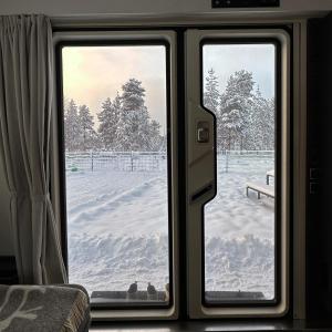 a view of a snow covered yard through a window at Santa`s luxury trailer in Rovaniemi