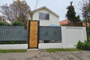 a white fence with a wooden door in front of a house at Casa cercana Mall Plaza Egaña in Santiago