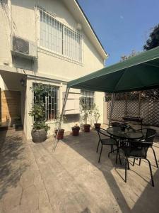 a patio with a table and chairs and a green umbrella at Casa cercana Mall Plaza Egaña in Santiago