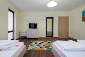 1 dormitorio con 2 camas, TV y espejo en ВИЛА МАРИНОВИ, en Boykovo