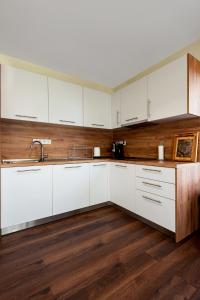 a kitchen with white cabinets and a wooden floor at ВИЛА МАРИНОВИ in Boykovo +26 photos