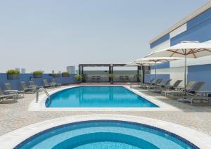 a pool on the roof of a building with chairs and umbrellas at Coral Dubai Deira Hotel in Dubai