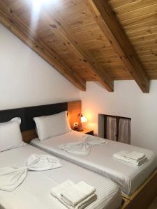 two beds in a room with wooden ceilings at Hotel Kaso Ervehe in Përmet
