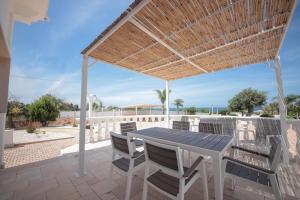 a patio with a table and chairs under a roof at Villa Ginevra la Dimora by Apulia Hospitality in Capitolo