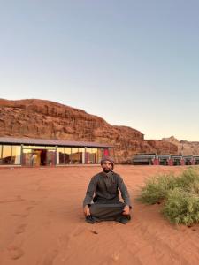 un hombre sentado en el suelo en el desierto en Wadi Rum Golden Valley en Wadi Rum
