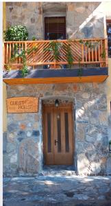 una casa in pietra con porta in legno e balcone. di Sanli a Mestia