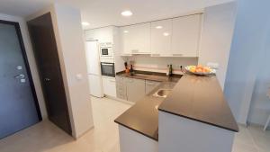a kitchen with white cabinets and a bowl of fruit on a counter at Nova Beach Apartment 41 in Gran Alacant +25 photos