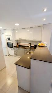 a kitchen with white cabinets and a black counter top at Nova Beach Apartment 41 in Gran Alacant