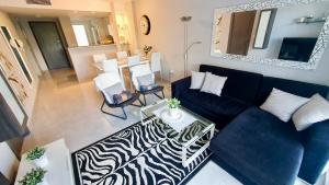 Nova Beach Apartment 41 في غران ألاكانت: غرفة معيشة مع أريكة زرقاء وطاولة