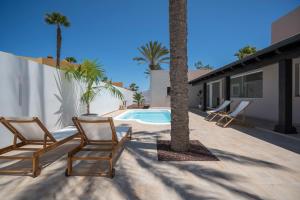 a patio with two chairs and a swimming pool at Villa Tropico - Design house with pool in Corralejo in Corralejo
