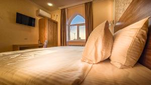 a bedroom with a bed with pillows and a window at Hotel Bankir Khiva in Khiva
