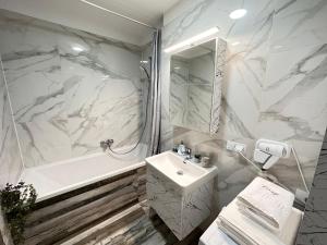 Baño blanco con lavabo y bañera en Deluxe Cozy Apartments - Coresi Mall #Brasov, en Brasov