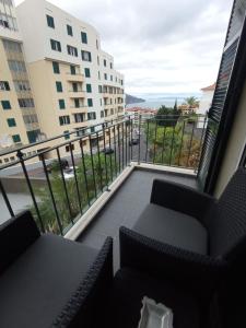 a balcony with chairs and a view of a city at Friendly house in Funchal