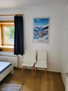 a bedroom with two white chairs and a window at Ferienwohnung Parsenn Peaks Panorama in Davos