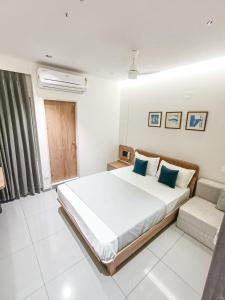 a white bedroom with a large bed and a couch at Hotel Kant by GoHotels - Best Hotel Near Shree Dwarkadhish Temple in Dwarka