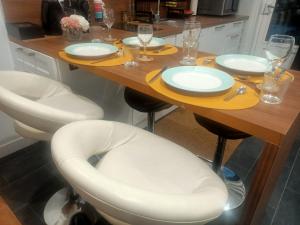 維尼西厄的住宿－Le Petit Cocon - Parking privé - Lyon Sud，一张桌子、两把白色椅子和一张木桌板