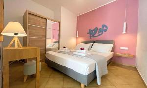 a bedroom with a bed with a desk and a pink wall at Art Apartment in Palaiochóra