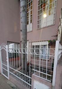 einen Zaun vor einem rosa Haus mit einem Baum in der Unterkunft a 3 MIN DEL CENTRO in Concordia