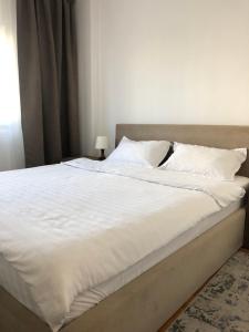 een groot bed met witte lakens en kussens bij Adrian Home, Central in Ploieşti