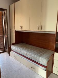 een bed in een kamer met witte kasten bij Appartamento Ladispoli in Ladispoli