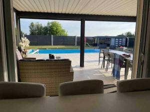 eine Terrasse mit einem Tisch, Stühlen und einem Pool in der Unterkunft Magnifique villa avec piscine chauffée in Cauroy-lès-Hermonville