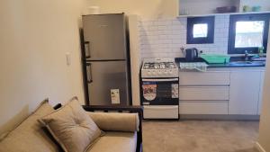 a kitchen with a refrigerator and a couch in a kitchen at Depto Edificio Vias Gualeguaychú, excelente in Gualeguaychú
