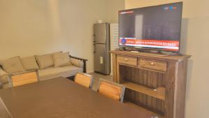 sala de estar con TV de pantalla plana en un soporte de madera en Depto Edificio Vias Gualeguaychú, excelente en Gualeguaychú
