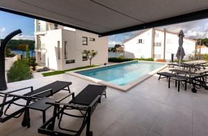 a patio with a swimming pool and tables and chairs at Villa Veronica with pool first line at sea in Palit