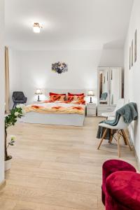 a white bedroom with a bed and a chair at La vie est belle in Bucharest
