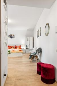 a white room with a bed and a red stool at La vie est belle in Bucharest