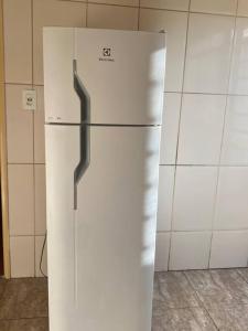 einen weißen Kühlschrank in einer Küche neben einer Wand in der Unterkunft Hospedaria Spring in Alfenas