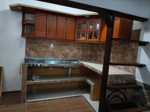 La cuisine est équipée d'un évier et de placards en bois. dans l'établissement Hotel Policarpa, à Guaduas