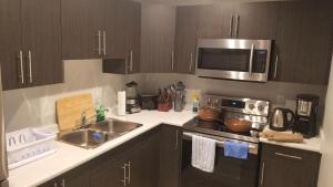 une cuisine avec un évier et un micro-ondes dans l'établissement Cozy, Comfortable, Convenient - Your Ideal 2BR Stay, à Saskatoon 19 autres photos