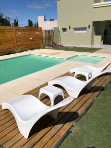 einen Pool mit zwei weißen Liegestühlen neben einem Pool in der Unterkunft casa quinta caballito blanco in Chascomús