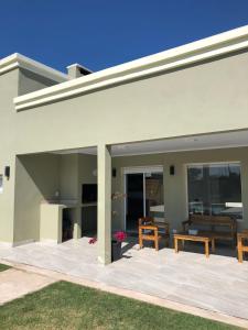 a white house with a patio with a table and benches at casa quinta caballito blanco in Chascomús +4 photos
