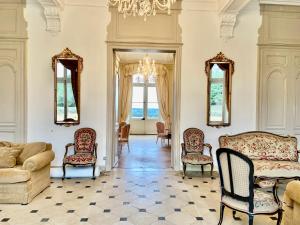 a living room with chairs and a couch and a chandelier at Château La Bainerie in Tiercé